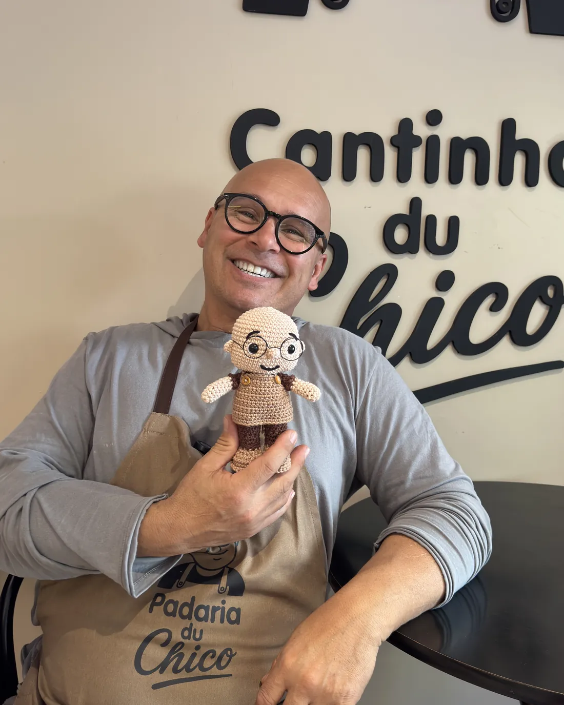 O Chico sorrindo com o mascote de crochê no Cantinho du Chico
